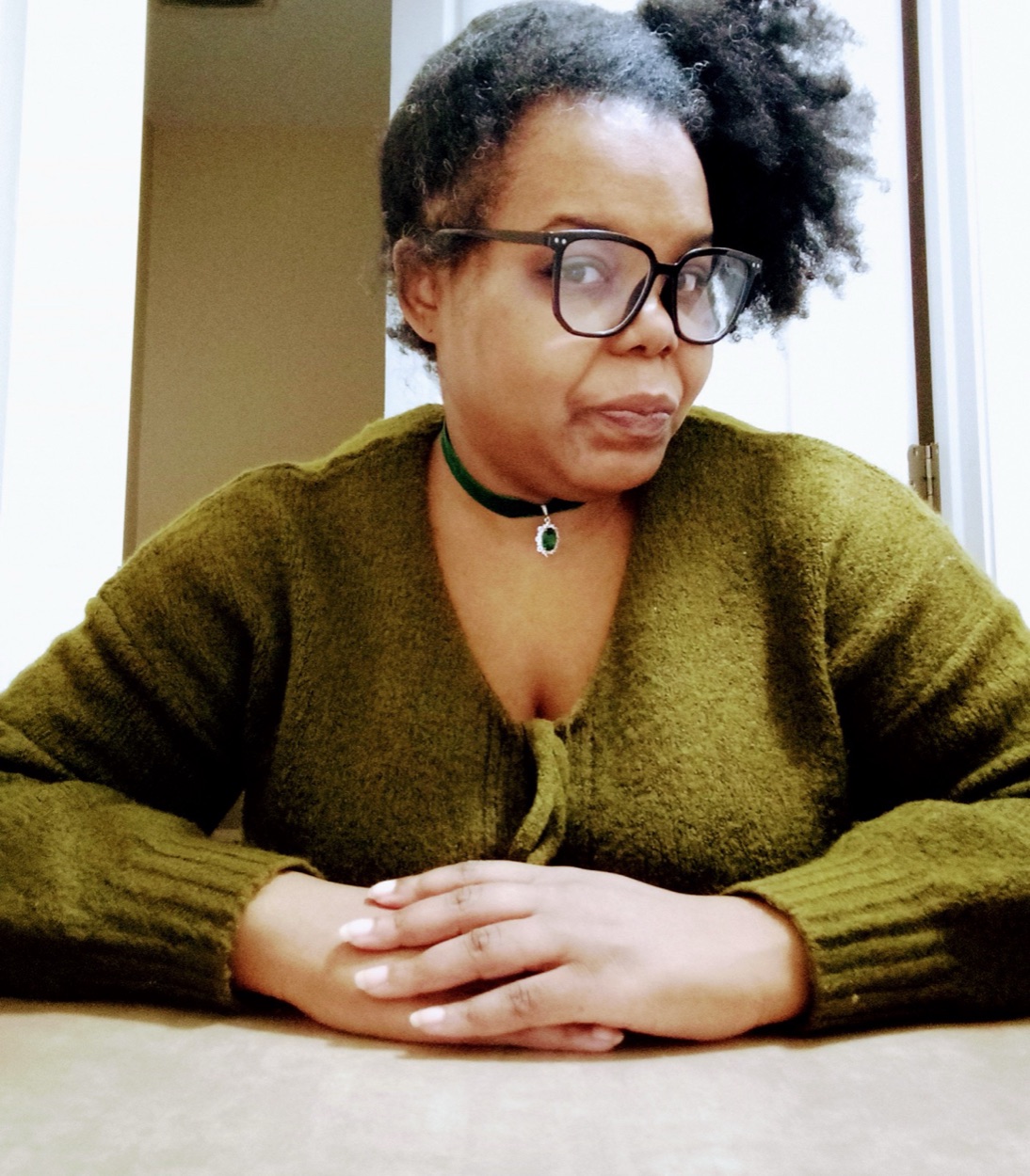 Kiki Parker at her table in a green sweater and glasses